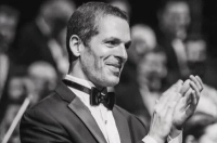 Black and white photo of a man in a tuxedo clapping Dr. Rick Hoffenberg Making Carnegie Hall Conducting Debut