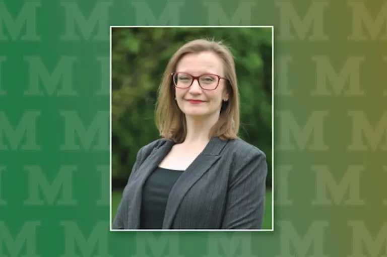 headshot of a woman wearing glasses and a gray blazer against a green backdrop with the Marywood M logo