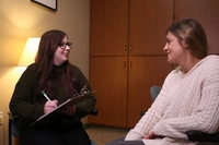 two young ladies talking, one has a clip board and a pen and paper What’s the Difference Between a Counselor, Therapist, Psychologist and Psychiatrist?