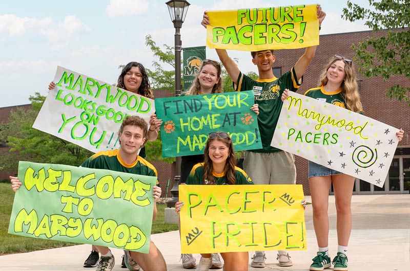 Students holding colorful green and yellow signs with Pacer Pride and Welcome to Marywood on them.